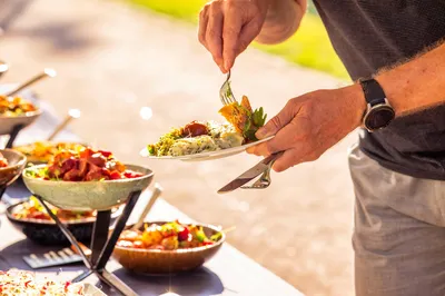 Bezoeker schept op van saladebar tijdens zomerse barbecue