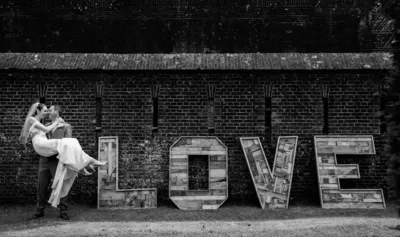 Bruid opgetild door bruidegom bij de love letters langs de fortmuur