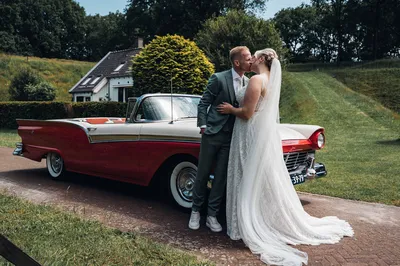 Bruidspaar voor klassieke auto in de forttuin