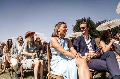Bruiloftsgasten tijdens ceremonie op zonnige dag met parasolletjes