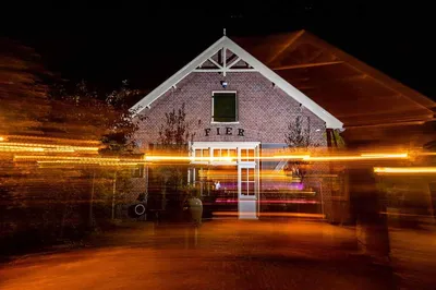 Buitenkant van de loods terwijl er een feest binnen gaande is