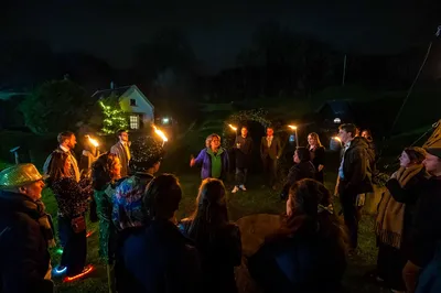 Een aantal bezoekers staan in een sfeervol licht klaar voor een rondleiding op het historische Unesco-fort