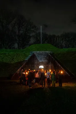 Een groepje mensen staat bij elkaar voor De Poterne in sfeervolle verlichting