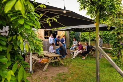 In De Forttuin staat een groepje mensen bij de buitenbar een drankje te drinken