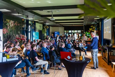 In De Loods bezoekers luisteren zittend naar een presentatie van een spreker