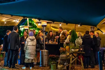 Onder een sfeervol verlichte Stretchtent staat een gezelschap met elkaar te praten