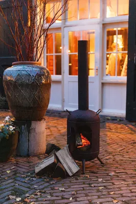 Sfeervolle brandende tuinhaard voor de mooi verlichte De Loods